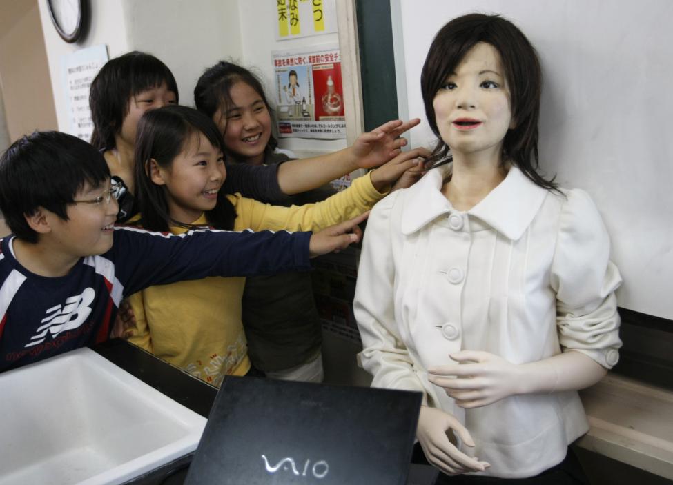 School pupils touch a humanoid robot named "Saya" as she takes on a role as a school teacher during a demonstration at an elementary school in Tokyo, Japan May 7, 2009. The robot can speak different languages and make facial expressions like happiness, surprise, sadness, fear, anger or disgust with motors inside her face. REUTERS/Issei Kato