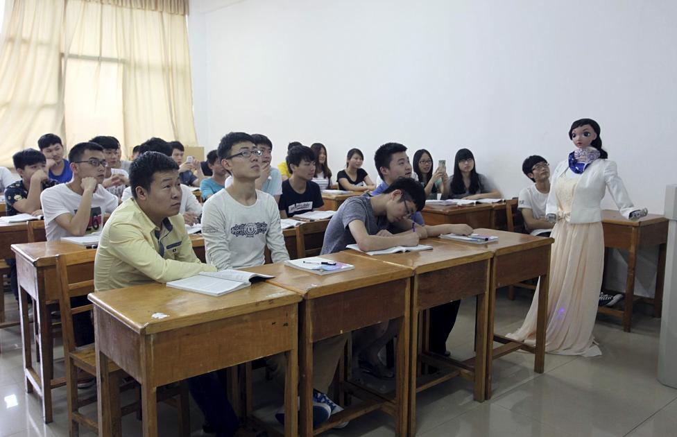 A robot teacher named "Xiaomei" (R) gestures during a demonstration at a class of Jiujiang University, in Jiujiang, Jiangxi province, China, June 3, 2015. The robot, designed and made by a team led by teacher Zhang Guangshun, is able to narrate the teaching materials and response to several voice orders like "repeat" or "continue". REUTERS/China Daily