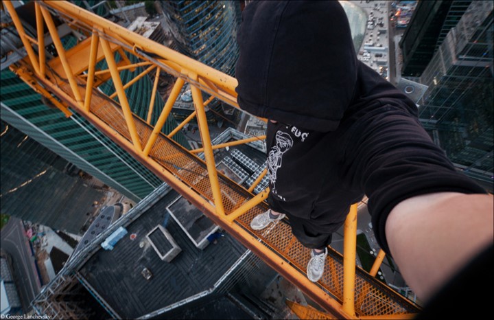 Moscow. VERTIGO inducing pictures from the top of a 155-foot-high crane have been captured by a photographer in bid to overcome his fear of heights. The amazing aerial images show the photographer and his friends throw caution to the wind as they precariously perch high above the cities with no safety equipment. Other shots capture the adventurous bunch in the middle of climbs up cranes and beautiful women posing on the edge of roof tops. The extreme photos were taken by Moscow photographer and acrophobic George Lanchevsky (24) in cities around the world including Moscow, Galich and Hong Kong.