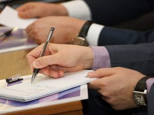 человек в костюме пишет на бумаге ручкой