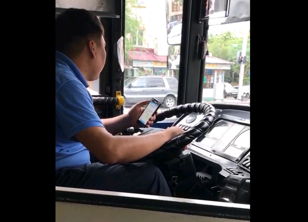 водитель автобуса с телефоном в руке